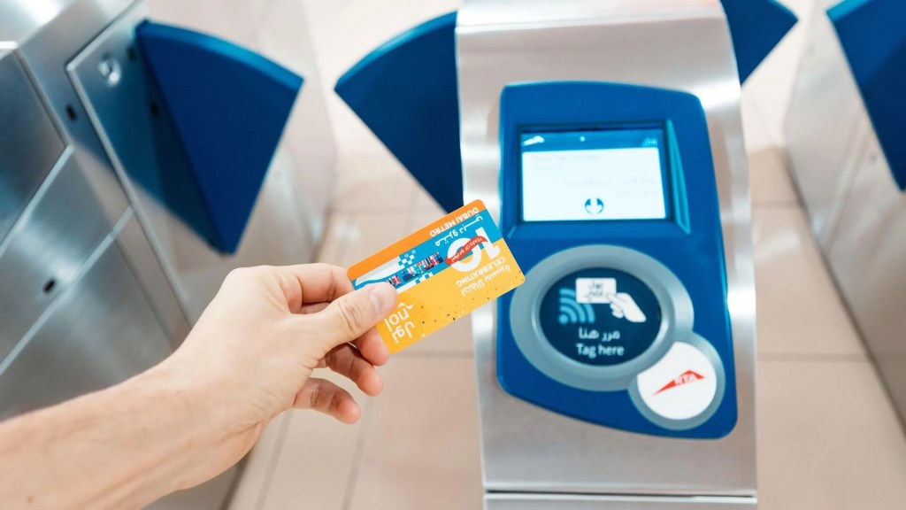 Person tapping Nol card at bus entrance with RTA logo visible