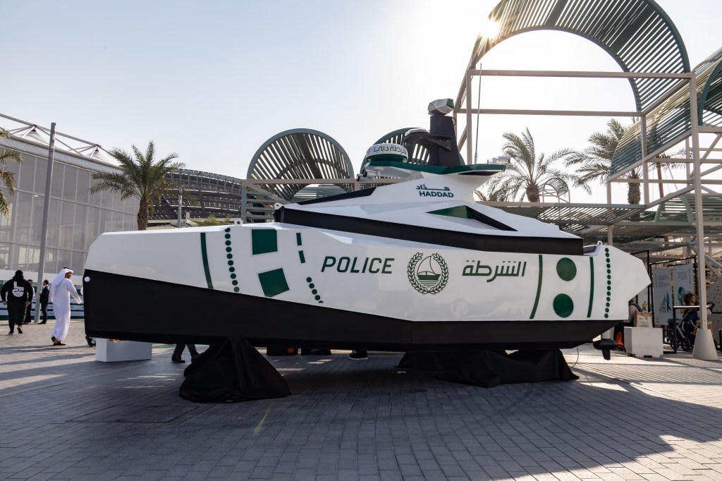 Dubai Police officers at the National Service Career Fair booth with recruitment information displays