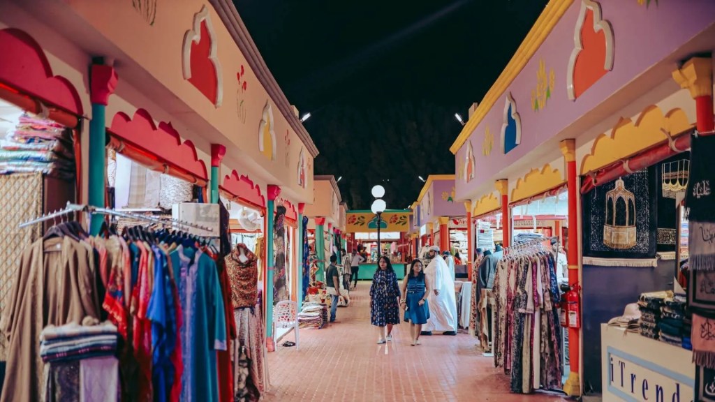 Traditional bazaar shopping experience inside Global Village pavilion with vendors and diverse visitors